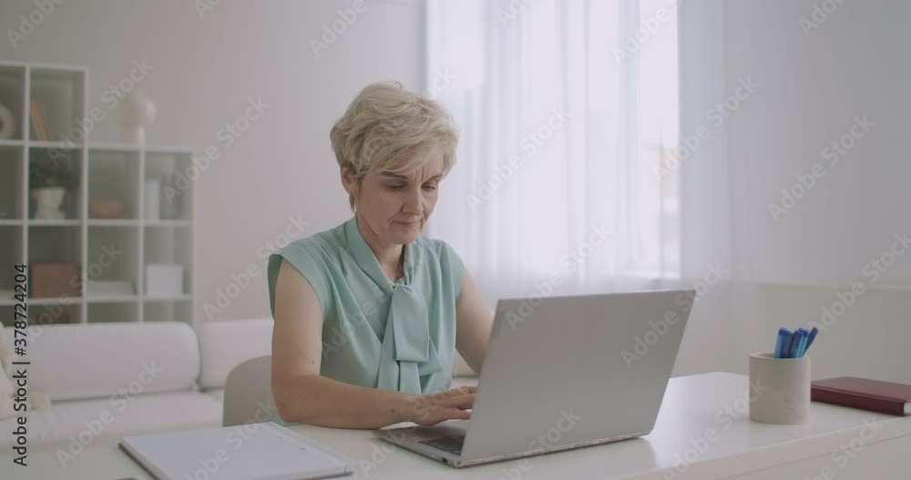 middle-aged blonde woman is communicating at social nets by laptop, using internet, typing message on keyboard middle-aged blonde woman is communicating at social nets by laptop, using internet, typing message on keyboard