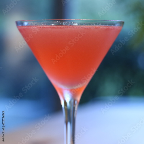 Cosmopolitan in Martini glass on wood table with garden background close up