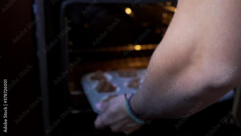 Follow shot of woman placing oven pan with homemade muffins in the oven at home 4K Follow shot of woman placing oven pan with homemade muffins in the oven at home 4K
