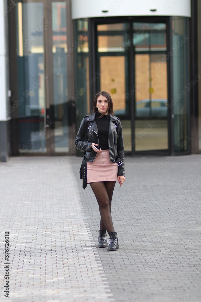 Beautiful young woman in black jacket  in the autumn city. 