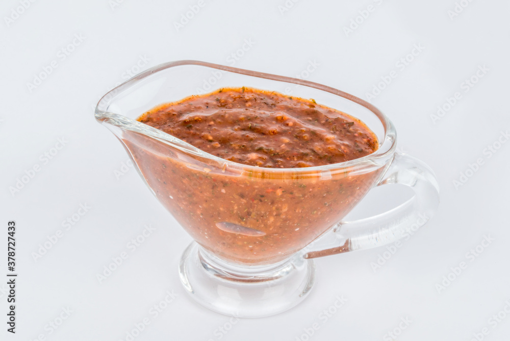 BBQ sauce in a transparent gravy boat shot on a white background BBQ sauce in a transparent gravy boat shot on a white background