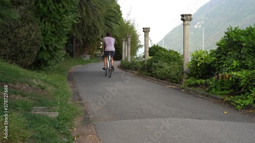 Guy drives a single-speed bicycle in his beautiful garden hallway surrounded by green nature and mountains. photo