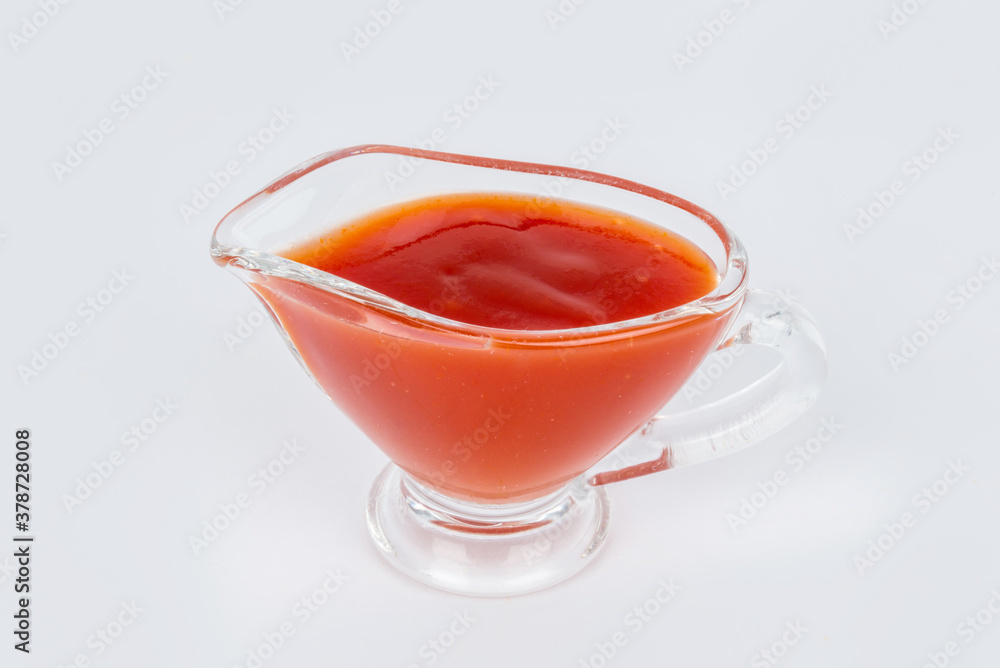 Sweet and sour sauce in a transparent gravy boat shot on a white background