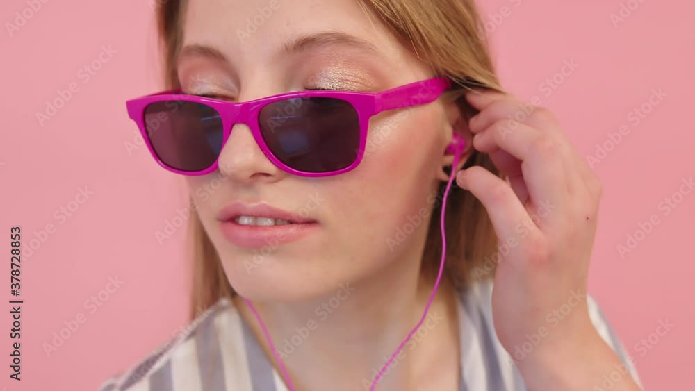Brunette Woman Wearing Pink Sunglasses And Earphones Grooving To The Music - close up, slow motion Brunette Woman Wearing Pink Sunglasses And Earphones Grooving To The Music - close up, slow motion