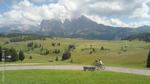 2/two people cycle through the beautiful mountains of Alm seiser, Alpe si Siusi in Ortisei/Urtijei, Dolomites, Italy, Europe on a sunny day photo