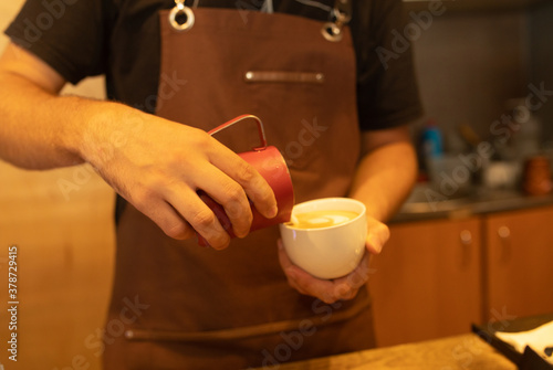 Hands pouring milk making latte art in a coffee.
