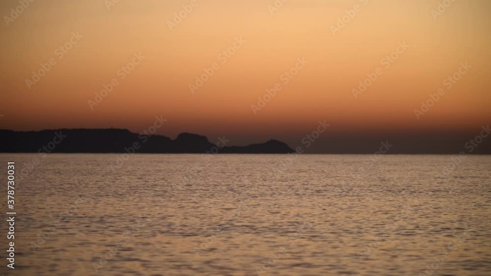 Orange sky over smooth water flow of mediterranean sea near Rhodes island Orange sky over smooth water flow of mediterranean sea near Rhodes island