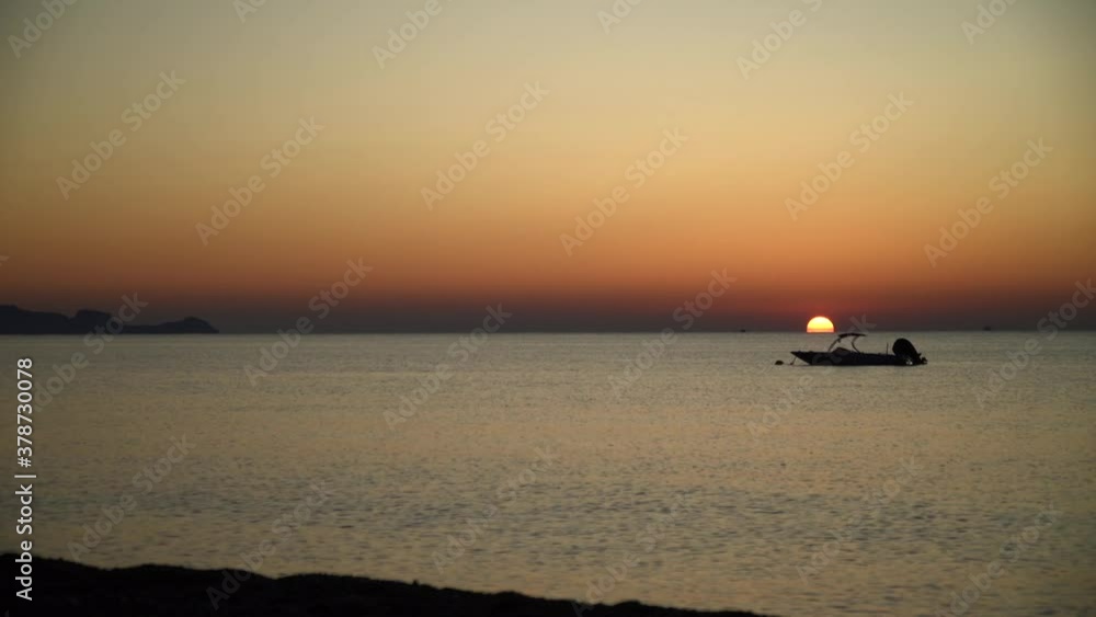 Golden fire sunrise on solo anchored boat in calm water near Rhodes island Golden fire sunrise on solo anchored boat in calm water near Rhodes island