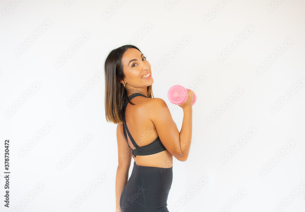 Woman doing exercise with a pink dumbbell while turning to look at the camera Woman doing exercise with a pink dumbbell while turning to look at the camera