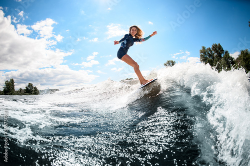 cheerful young woman actively ride surfboard on the wave