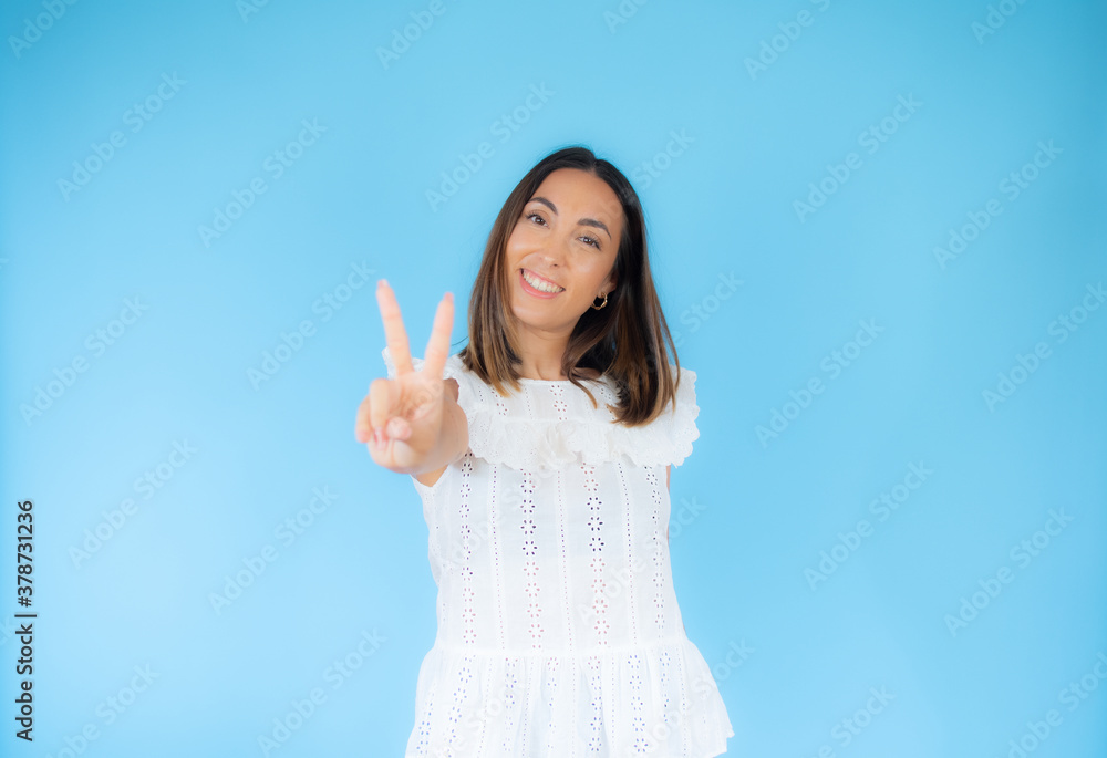 Woman in white clothes doing the victory symbol with her hand facing the camera Woman in white clothes doing the victory symbol with her hand facing the camera