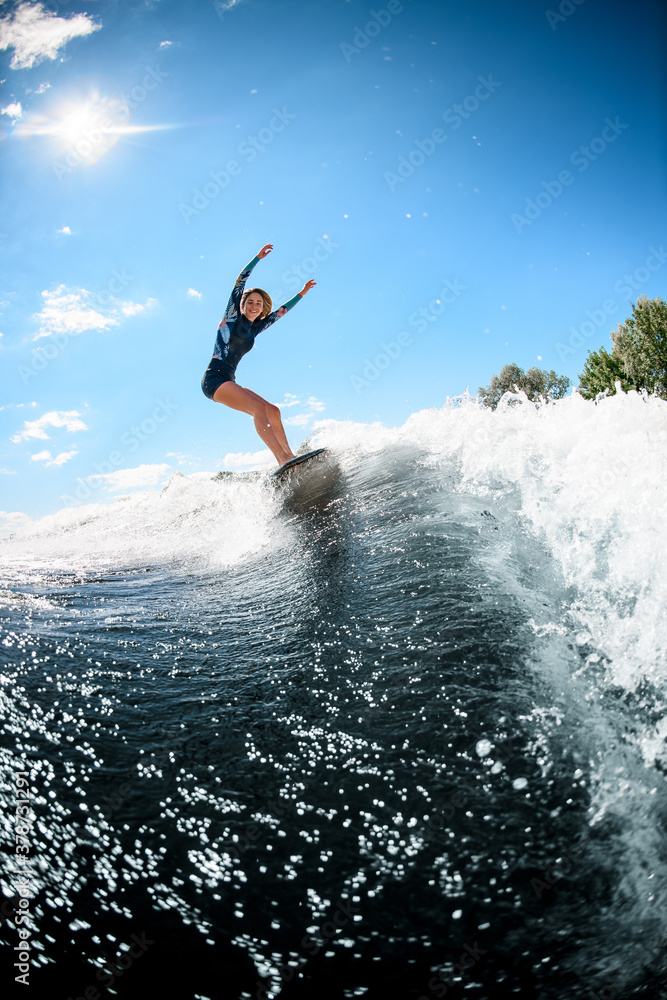view on handsome young woman actively ride surfboard on the wave