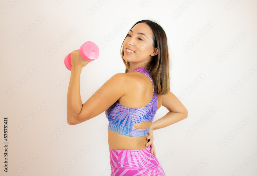 Woman in sportswear holding a pink dumbbell Woman in sportswear holding a pink dumbbell