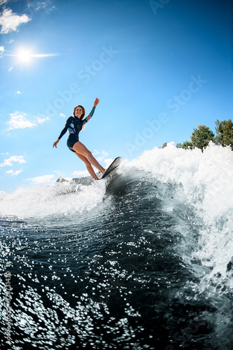 view on beautiful smiling woman actively ride surfboard on the wave