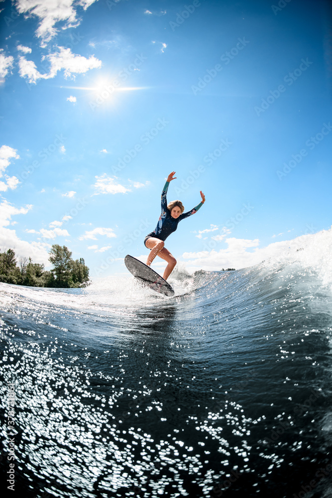 energetic young woman in swimsuit rides on river wave