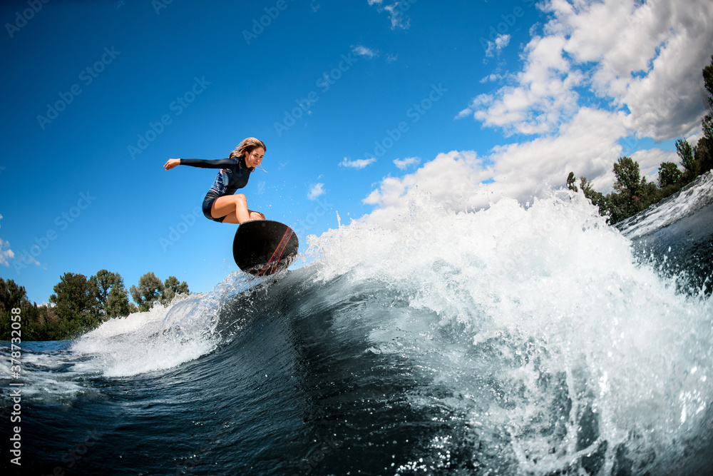 woman on surfboard jumping over the wave