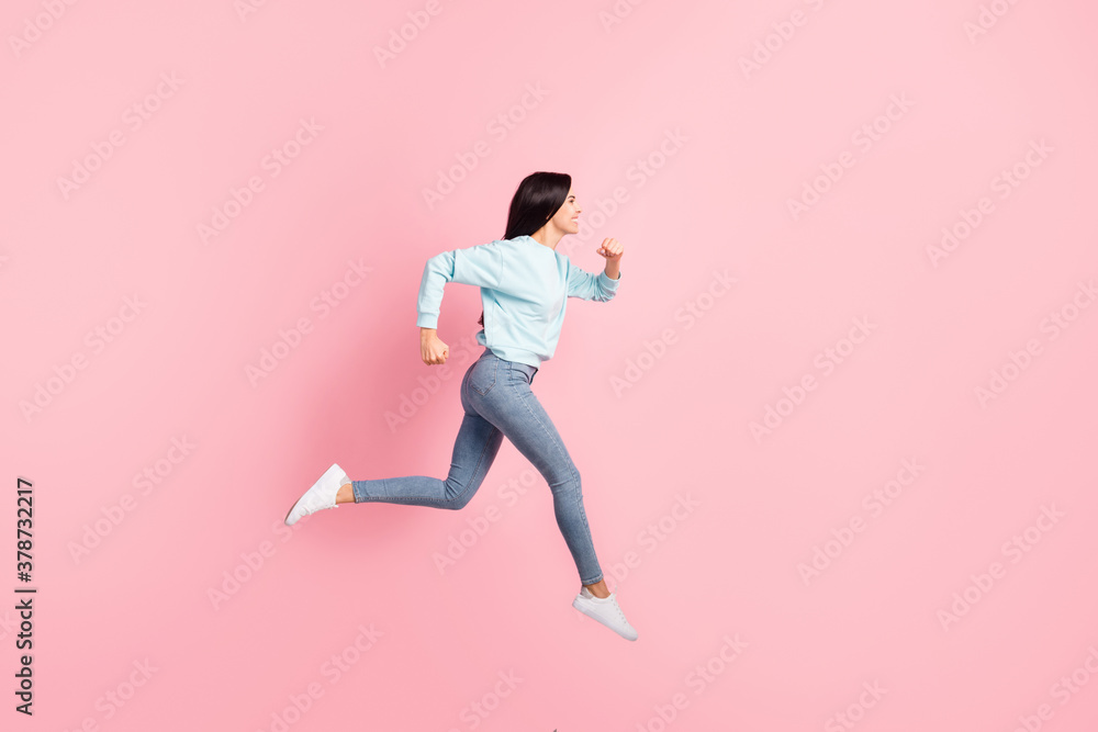 Full length profile photo lady jumping running speed flying in air wear blue pullover jeans isolated pink color background Full length profile photo lady jumping running speed flying in air wear blue pullover jeans isolated pink color background