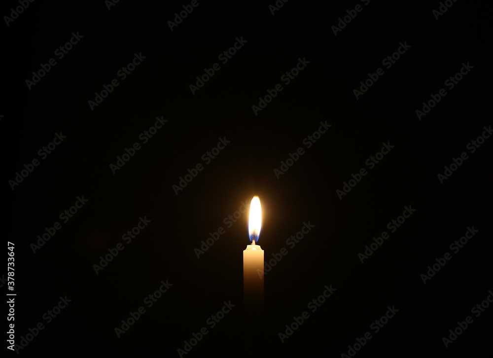 Light of hope - Candle is burning against black background Light of hope - Candle is burning against black background