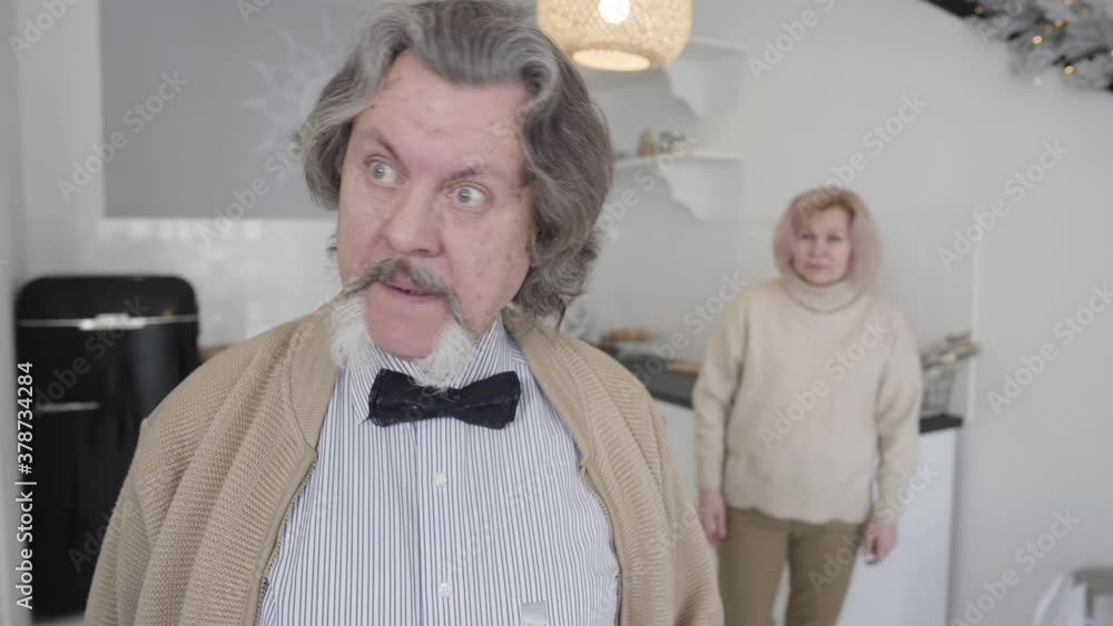 Annoyed senior man looking back at blurred woman gesturing at the ...