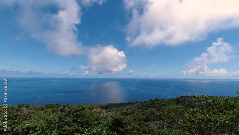 Fast moving cloud timelapse over open blue ocean with reflections of clouds in water with island in foreground Fast moving cloud timelapse over open blue ocean with reflections of clouds in water with island in foreground