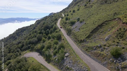 Drone pull back shot of cars driving up steep winding mountain road photo