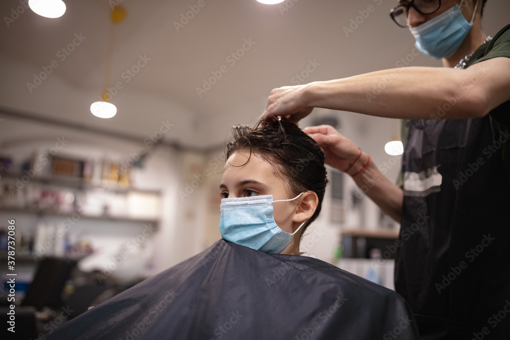 Hairdresser and girl child customer in a salon with medical masks during virus pandemic. Working with safety mask. Hairdresser and girl child customer in a salon with medical masks during virus pandemic. Working with safety mask.