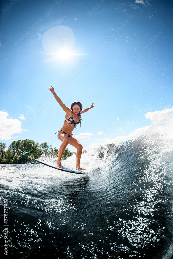 beautiful woman in bright swimsuit jumps on the waves on surfboard.