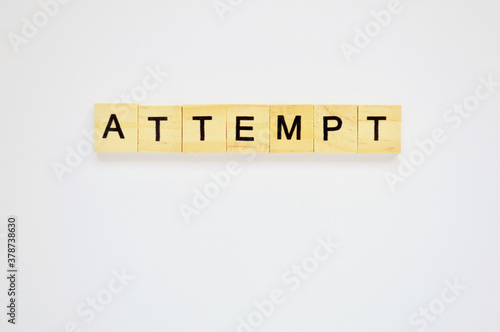 Word attempt. Wooden blocks with lettering on top of white background. Top view of wooden blocks with letters on white surface