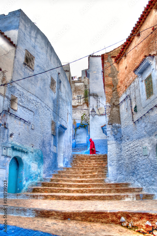 Berber in red cloak walking streetof Chefchauen Morocco