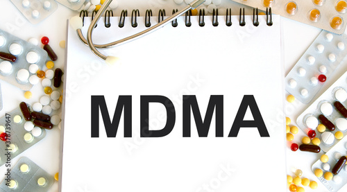 Text MDMA on a white background. Nearby are various medicines. Medical concept. photo