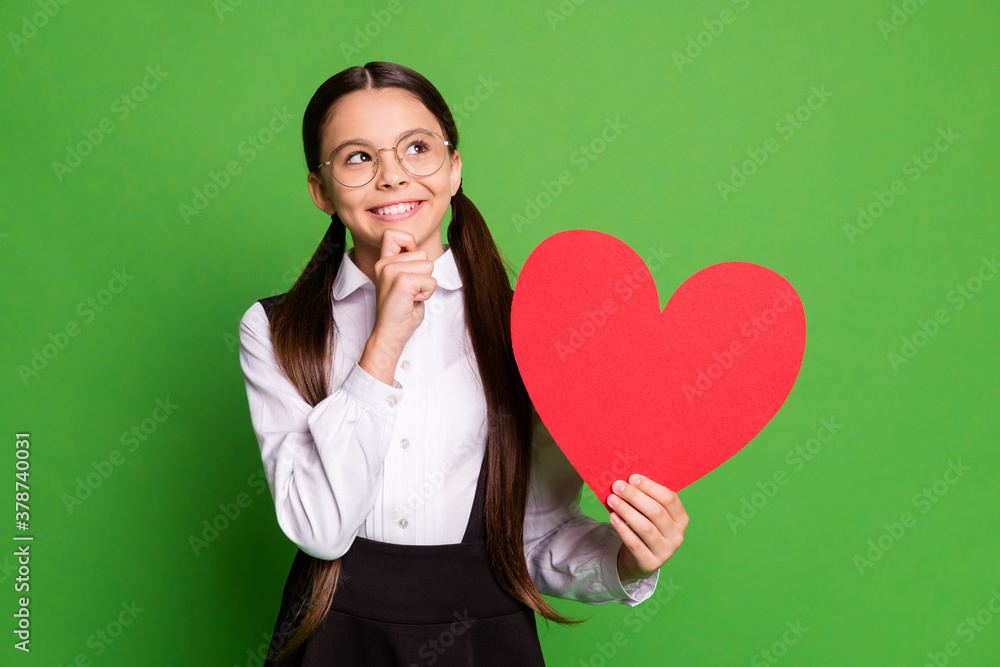 Photo of pretty cunning little schoolkid lady in front of blackboard hold show paper red heart figure look up empty space hand chin wear white shirt glasses isolated green color background Photo of pretty cunning little schoolkid lady in front of blackboard hold show paper red heart figure look up empty space hand chin wear white shirt glasses isolated green color background