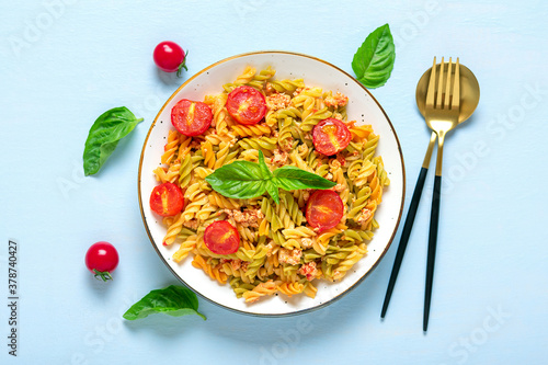 Fusilli - classic italian pasta from durum wheat with chicken meat, tomatoes cherry, basil in tomato sauce in white bowl on blue wooden table Mediterranean cuisine Top view Flat lay