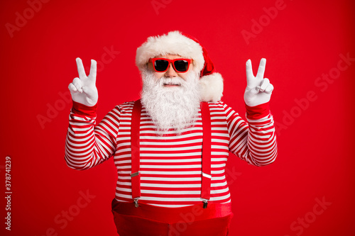 Portrait of his he nice attractive handsome cheerful cheery optimistic Santa showing double v-sign having fun party good mood isolated on bright vivid shine vibrant red color background © deagreez