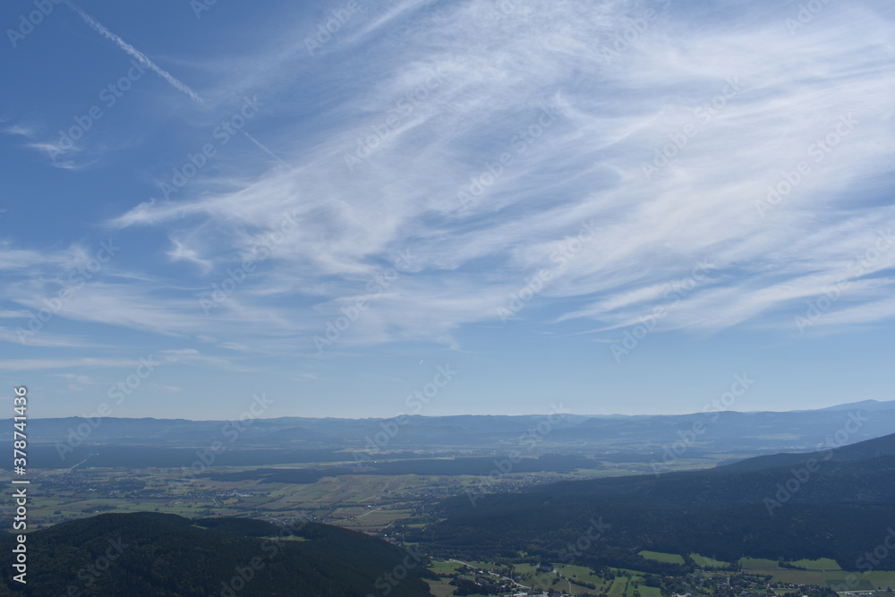 Weite Landschaft mit Hügeln, Bergen und Feldern, blauer Himmel mit zarten Wolken als Hintergrund für Fremdenverkehr, Tourismus