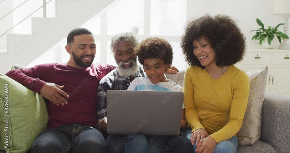 Multi-generation family using laptop on couch at home Multi-generation family using laptop on couch at home