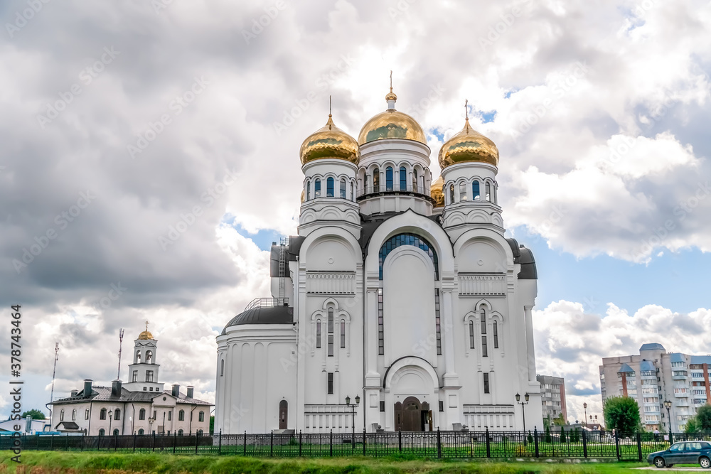 White Church with Golden domes with Eastern Orthodox crosses against a blue sky with clouds