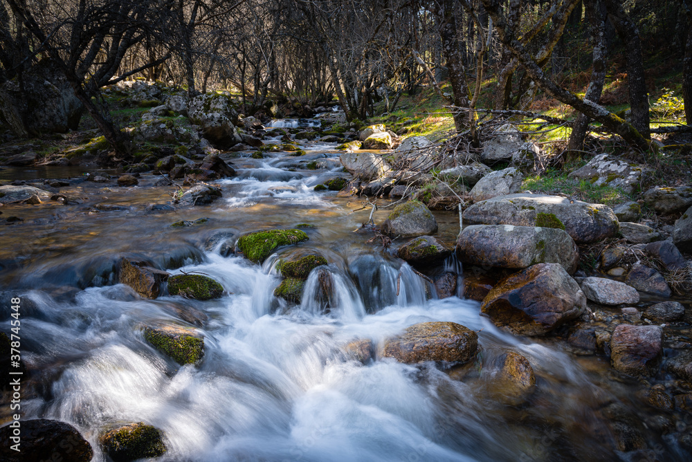 River water flows among the rocks and forms small waterfalls, Rascafría, Madrid, Spain River water flows among the rocks and forms small waterfalls, Rascafría, Madrid, Spain