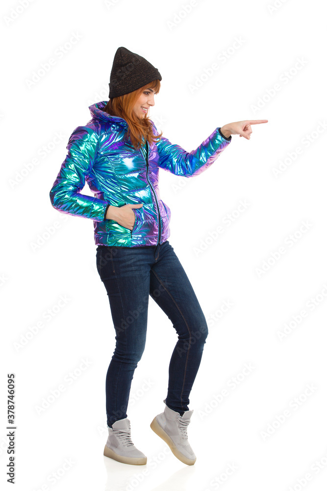 Young Woman In Vibrant Down Jacket Is Pointing Or Touching Something. Young Woman In Vibrant Down Jacket Is Pointing Or Touching Something.