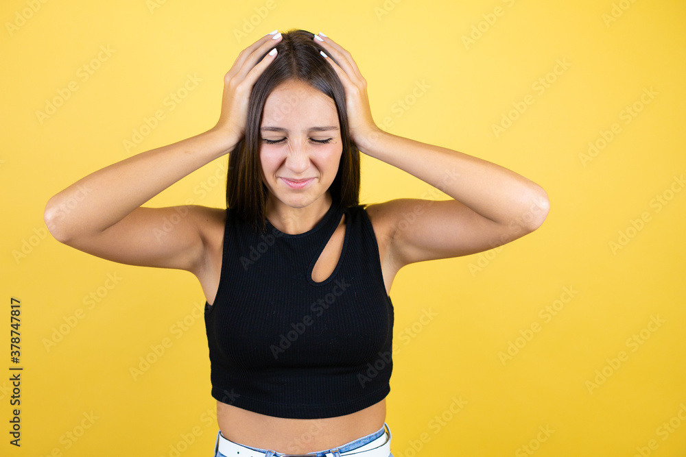 Beautiful young girl kid over isolated yellow background suffering from headache desperate and stressed because pain and migraine with her hands on head Beautiful young girl kid over isolated yellow background suffering from headache desperate and stressed because pain and migraine with her hands on head