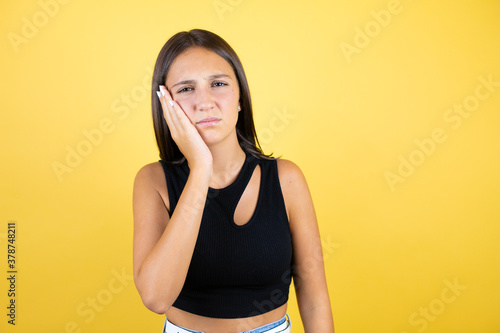 Beautiful young girl kid over isolated yellow background touching mouth with hand with painful expression because of toothache or dental illness on teeth