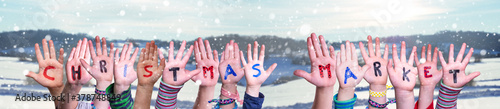 Children Hands Building Colorful English Word Christmas Market. Snowy Winter Background With Snowflakes