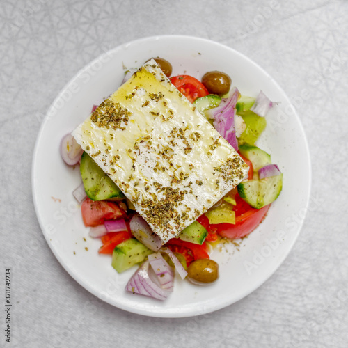 original feta cheese in Greek salad plate, top view close up