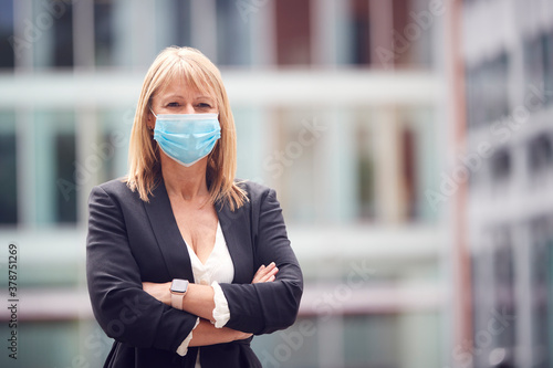 Portrait Of Mature Businesswoman Wearing PPE Face Mask Outdoors In Street During Health Pandemic