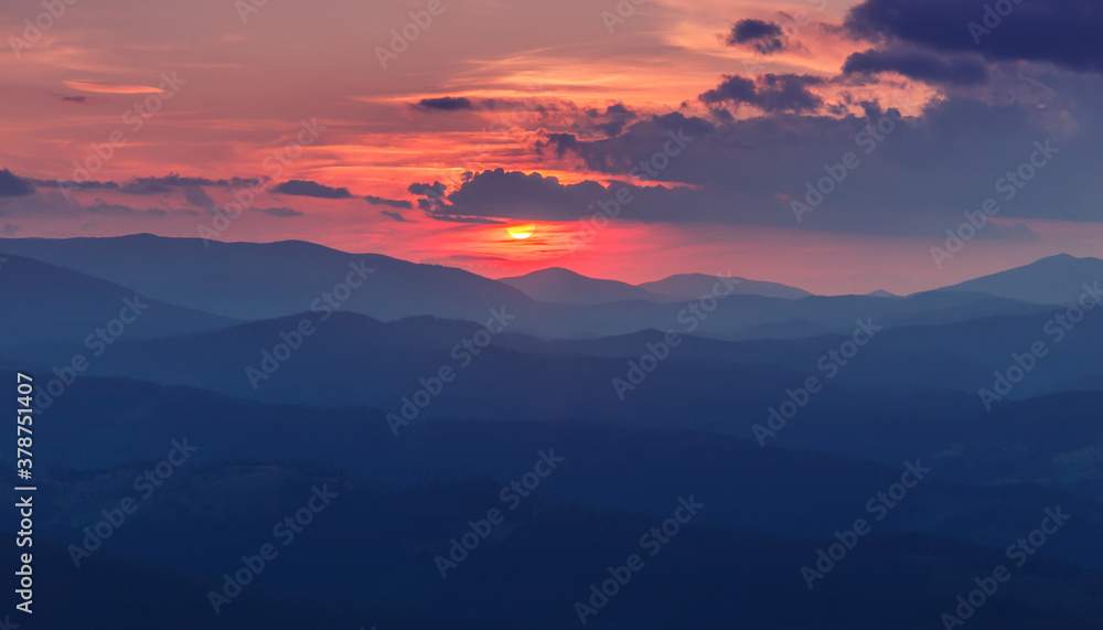 Amazing mountain landscape with picturesque vivid sunset. Amazing Natural background. Stunning nature scenery of Carpathian. dramatic foggy morning with mountains silhouette and red, blooddy sky