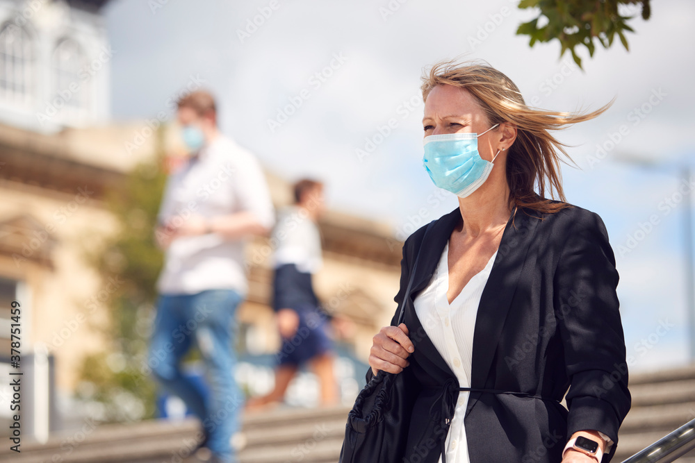 Obraz premium Mature Businesswoman Wearing PPE Face Mask Walking Outdoors In Street During Health Pandemic