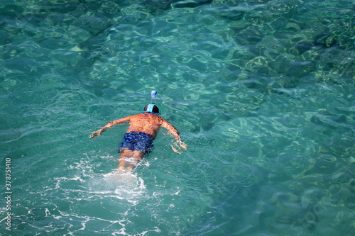 Snorkeling in the sea, beach vacation. Man in mask swim in a clear blue water, top view