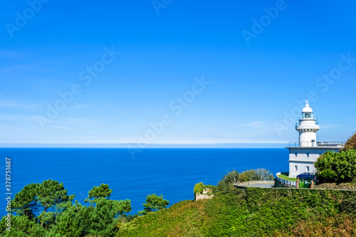 white lighthouse on the shore against the blue sea. Donostia San Sebastian, Basque Country, Spain. Copy space