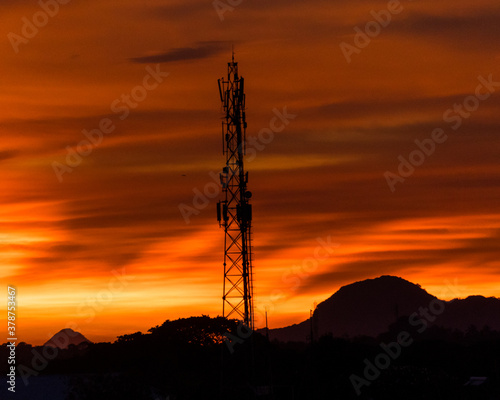 Tower amidst mountains in sunset. the shades of clouds in the sky is something that enhances beauty of the picture.