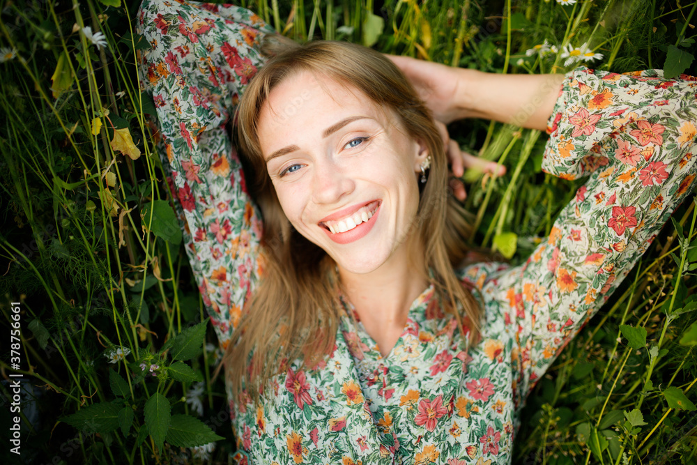 Portrait of Beautiful smiling blonde girl laying on green grass in wild nature Portrait of Beautiful smiling blonde girl laying on green grass in wild nature