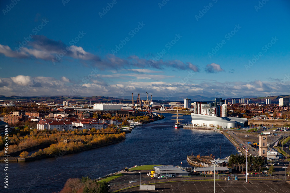 Glasgow, Scotland - Fall in the city. Clyde river embankment. Riverside Museum and The Tall Ship at Riverside. Panorama view. Yellow trees. Blue sky, clouds.